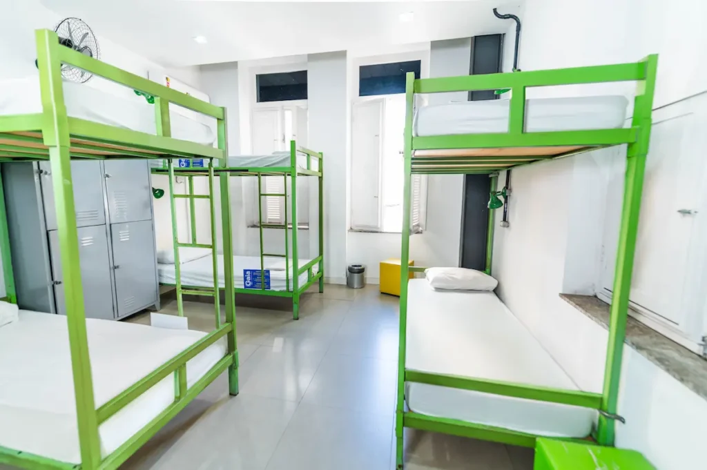 Vista interna do dormitório compartilhado com armários individuais (lockers), ventilador e ar-condicionado no Gaia Hostel.