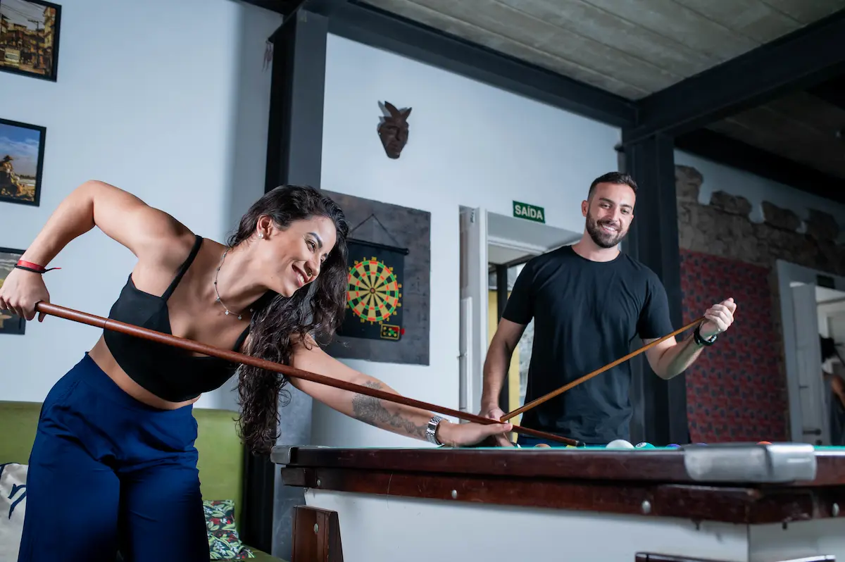 Mulher jogando sinuca em sala de jogos de hostel em Botafogo.